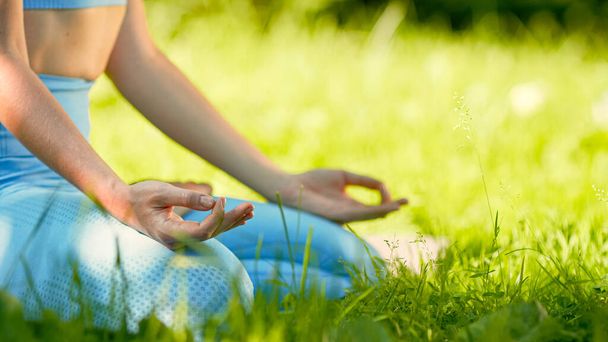 Yoga praticante signora in tuta blu tiene le mani sulle ginocchia unendo pollici - Foto, immagini