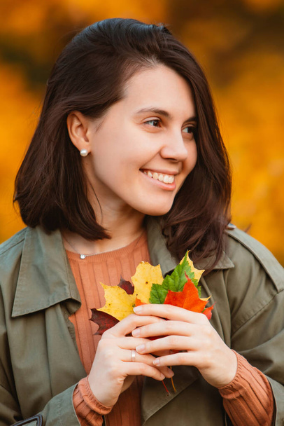 黄金の秋の葉の前の美しい笑顔の女性 - 写真・画像