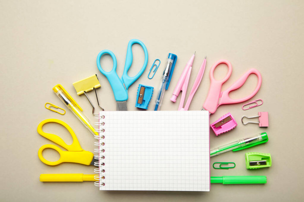 Blue, yellow, pink, green school supplies on grey background. Back to school concept. Top view. - Photo, image