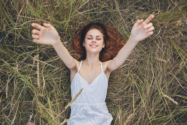 Femme en robe blanche se trouve sur le champ d'herbe nature amusant - Photo, image