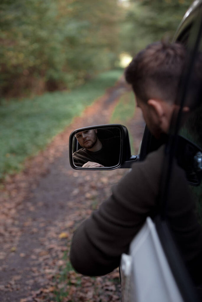 Porträt eines Mannes ragt am Waldweg aus Autofenster - Foto, Bild