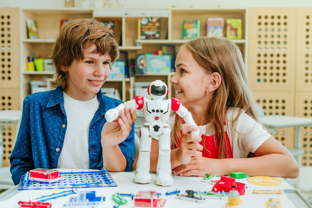 Tinédzser fiú és lány játszani robot közben leckét az osztályteremben. - Fotó, kép
