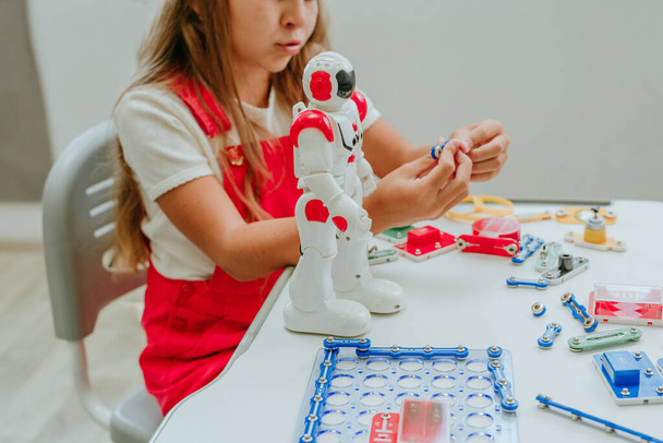 Девочка-подросток играет с роботом во время урока в классе. - Фото, изображение