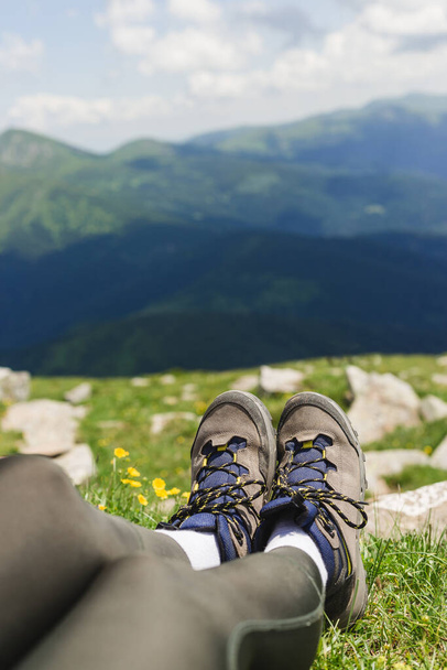 Traveler hiking boots on Beautiful mountain landscape view. Tourism or Freedom concept. Legs of traveler sitting making feet selfie on a high mountain in travel. - Photo, Image