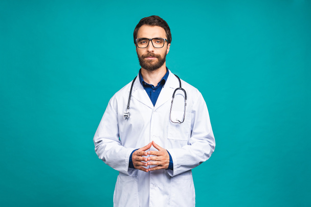 Muotokuva nuori parrakas lääkäri, jolla on stetoskooppi kaulassa lääketieteellisessä takissa seisomassa eristettyä sinistä taustaa vasten. - Valokuva, kuva