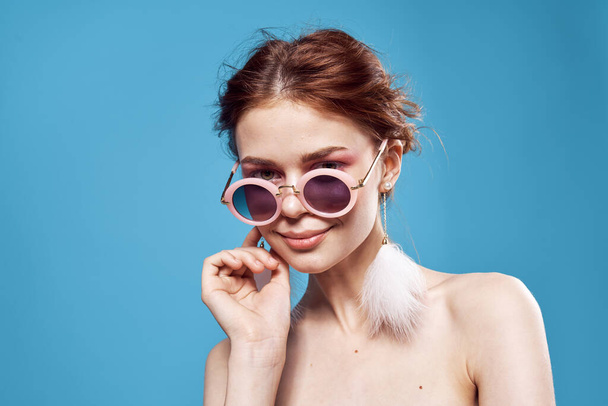 woman bare shoulders fluffy earrings fashion glasses close-up - Foto, afbeelding