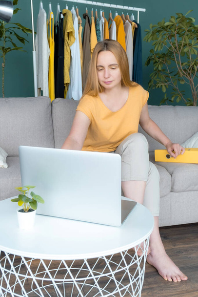 Moyen Age Blond Femme assise sur le canapé et communique en ligne par ordinateur portable. - Photo, image