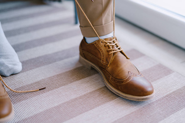 Man is tightening the laces on the brown brogues. Close-up - Fotografie, Obrázek