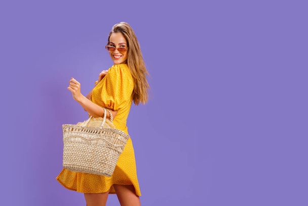 Fashionable woman in nice yellow dress and straw handbag. Fashion spring summer photo - Valokuva, kuva