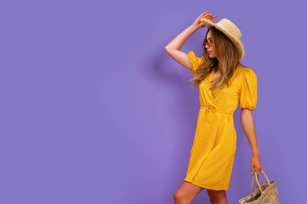 Beautiful young woman in white dress, summer straw hat, sunglasses, straw bag isolated on pastel violet background.  - Φωτογραφία, εικόνα
