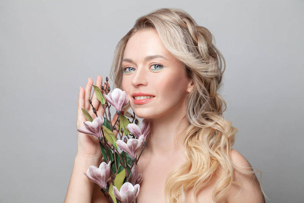 Porträt einer charmanten verträumten Frau mit perfekter natürlicher ästhetischer Haut und gesundem Haar auf grauem Hintergrund - Foto, Bild