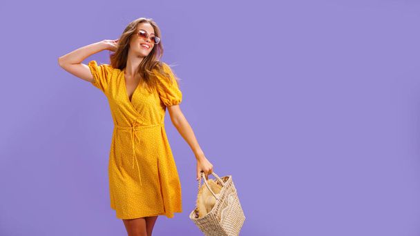 Fashionable woman in nice yellow dress and straw handbag. Fashion spring summer photo - Photo, Image