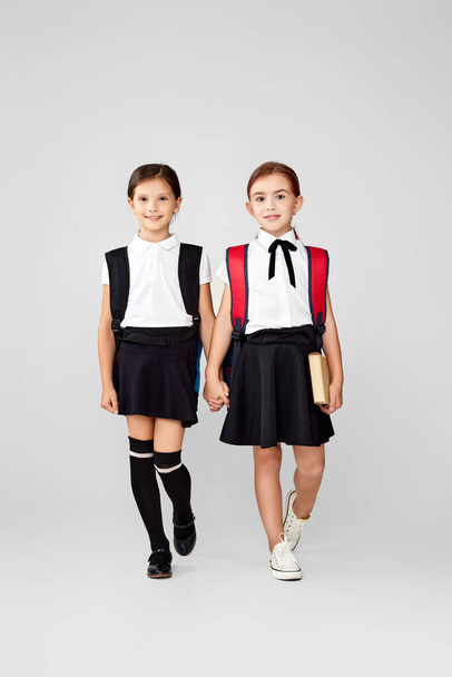 two happy little cheerful friends schoolgirls with backpacks - Photo, image