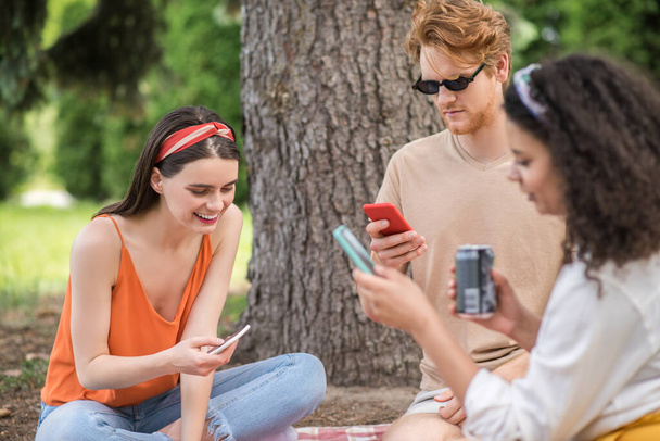 Guy and girls with smartphones at picnic - Фото, зображення
