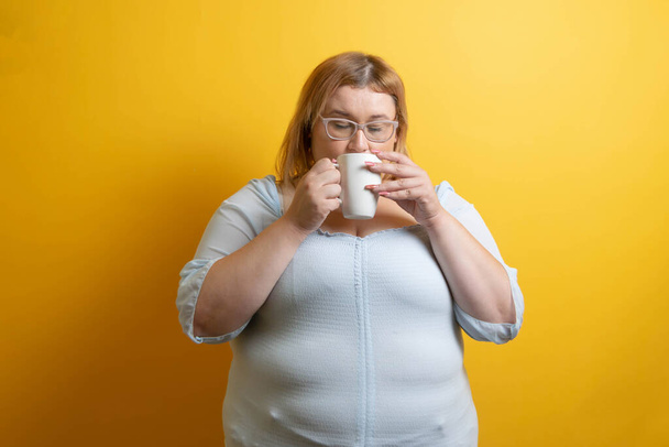bílá a baculatá mladá žena pije šálek kávy. osoba s nadváhou - Fotografie, Obrázek