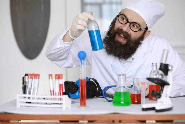Kemisti hullu. Hullu tiedemies tekee kokeita tieteellisessä laboratoriossa. Suorittaa tutkimusta mikroskoopilla. - Valokuva, kuva
