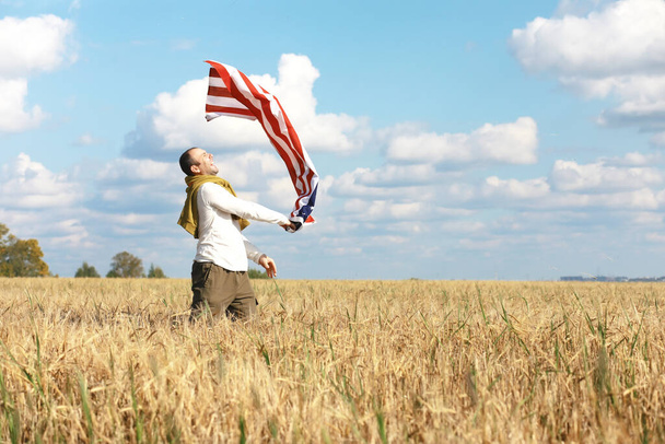 Άνθρωπος κυματίζει αμερικανική σημαία στέκεται στο γεωργικό τομέα αγρόκτημα, διακοπές, πατριωτισμός, υπερηφάνεια, ελευθερία, πολιτικά κόμματα, μετανάστης - Φωτογραφία, εικόνα