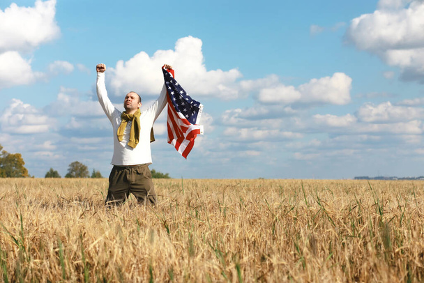 Uomo che sventola bandiera americana in piedi in campo agricolo, vacanze, patriottismo, orgoglio, libertà, partiti politici, immigrati - Foto, immagini