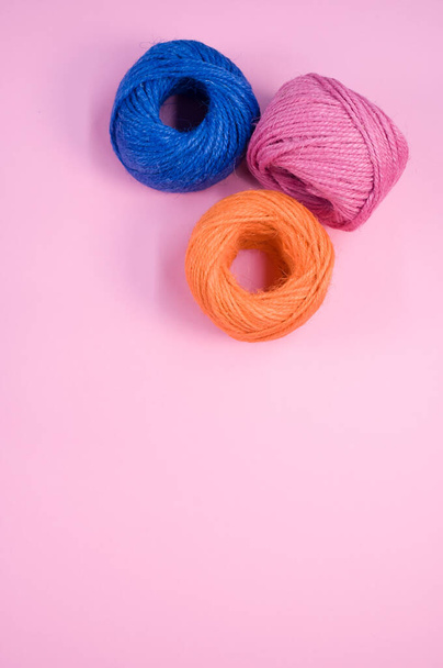 A vertical shot of colorful cotton threads on a pink background - Fotoğraf, Görsel
