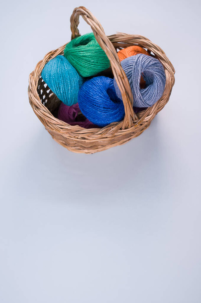 A vertical shot of colored cotton threads in a basket on a white background - Фото, зображення