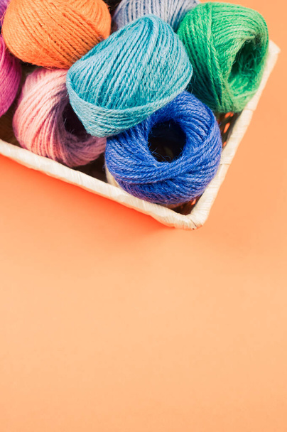 A basket full of colorful yarn rolls isolated on an orange background with free space for text - Fotografie, Obrázek