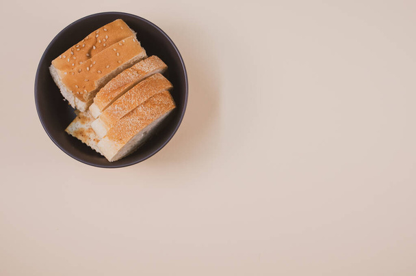 A bowl with bread slices isolated on a beige background with free space for text - Fotografie, Obrázek