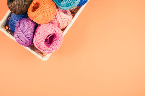 A basket full of colorful yarn rolls isolated on an orange background with free space for text - Foto, Bild