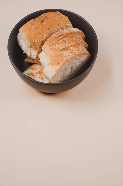 A bowl with bread slices isolated on a beige background with free space for text - Foto, imagen