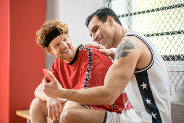 Two basketball players sitting in a changing room and talking - Фото, зображення