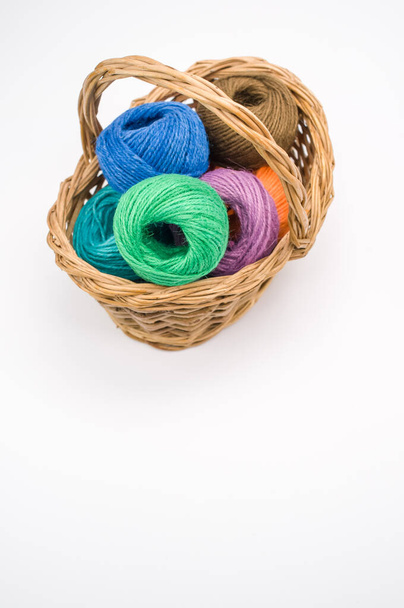A vertical shot of colored cotton threads in a basket on a white background - Foto, immagini