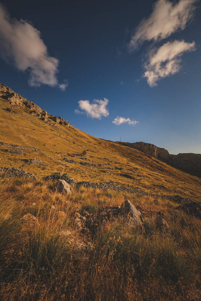 A rocky mountain with grass on it under the blue sky - Foto, Bild