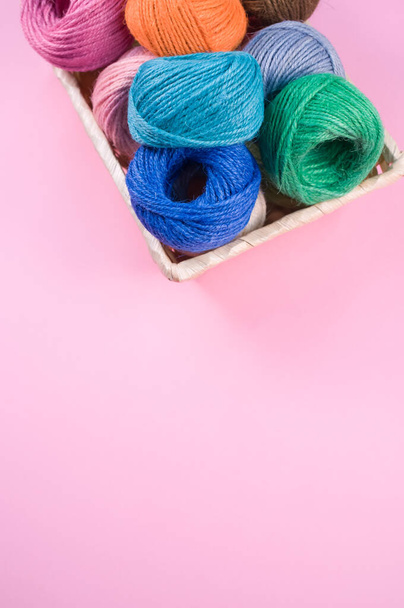A basket full of colorful yarn rolls isolated on a pink background with free space for text - Fotografie, Obrázek
