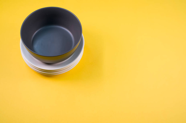 A top view of an empty ceramic black and white plates on a yellow background - Fotoğraf, Görsel