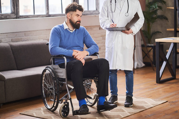 Man with disability listening to a doctor in his home - Foto, afbeelding