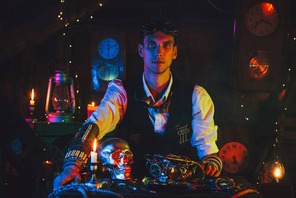 Steampunk εφευρέτης άτομο σε ένα κοστούμι σε ένα τραπέζι με διάφορους μηχανισμούς - Φωτογραφία, εικόνα