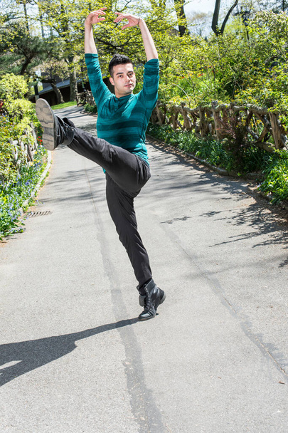 Stretching braccia e gambe, un giovane bel ragazzo sta ballando in un parco.  - Foto, immagini
