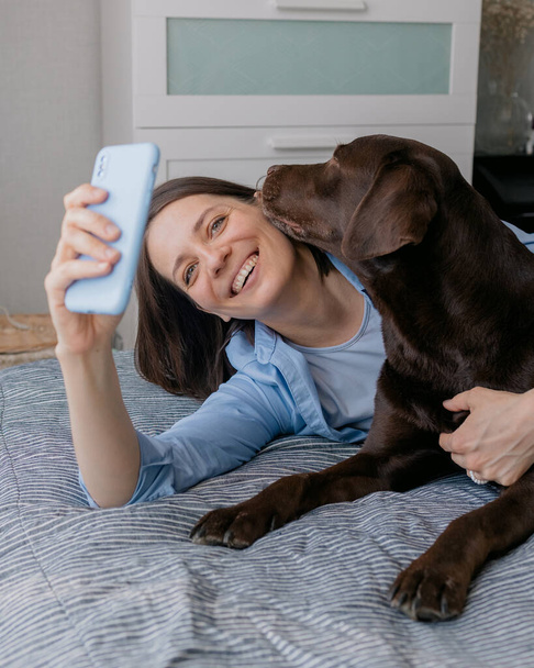 felice donna europea e il suo cane labrador retriever a casa felice donna europea e il suo cane labrador retriever a casa prendendo selfie sul suo smartphone - Foto, immagini