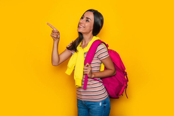 Happy cute student girl in modern casual clothes with pink backpack is posing in studio - Foto, Imagem