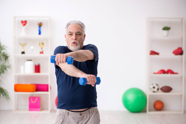 Old man doing sport exercises indoors - Foto, imagen