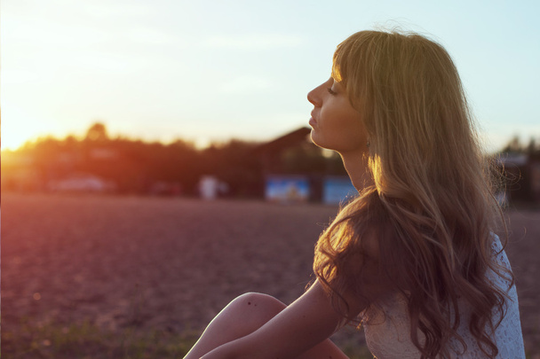 Молодая женщина, гуляющая по пляжу под лучами заката, портрет на открытом воздухе. Мягкий свет и солнце
. - Фото, изображение