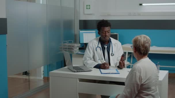 Дорослий лікар африканської етнічної приналежності дає пляшку таблеток
 - Кадри, відео