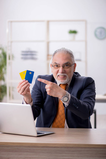 Ancien employé masculin titulaire d'une carte de crédit au bureau - Photo, image