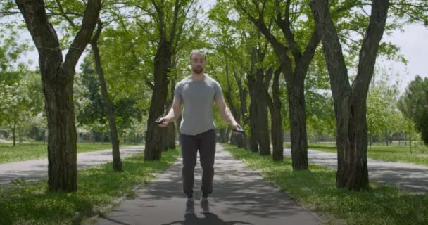Sportowy młodego człowieka skakanka w parku - Materiał filmowy, wideo