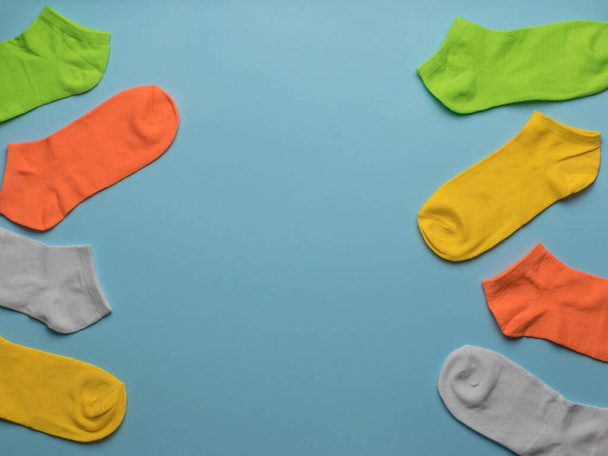 Multicolored short socks on a blue background. A stylish sports accessory. Flat lay. - Foto, afbeelding
