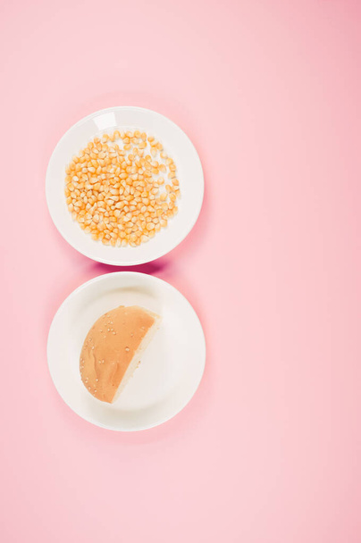 A vertical shot of corn and half bread on a pink background - Foto, imagen