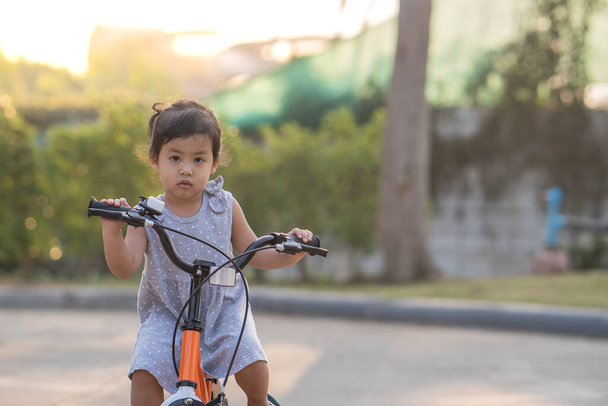 A cute little Thai girl riding a bicycle - Photo, Image