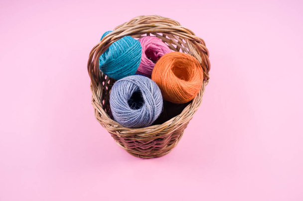 A closeup shot of colored cotton threads in a basket on a pink background - Zdjęcie, obraz