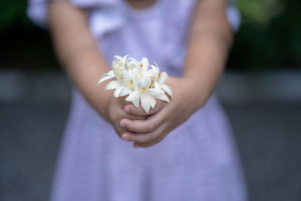 A cute little girl holding beautiful white flowers - Fotoğraf, Görsel