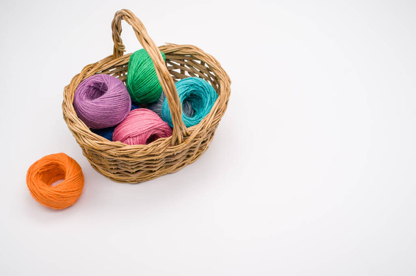 A closeup shot of colored cotton threads in a basket on a white background - Foto, afbeelding