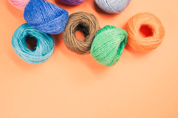 A closeup shot of colored cotton threads on an orange background - Foto, afbeelding